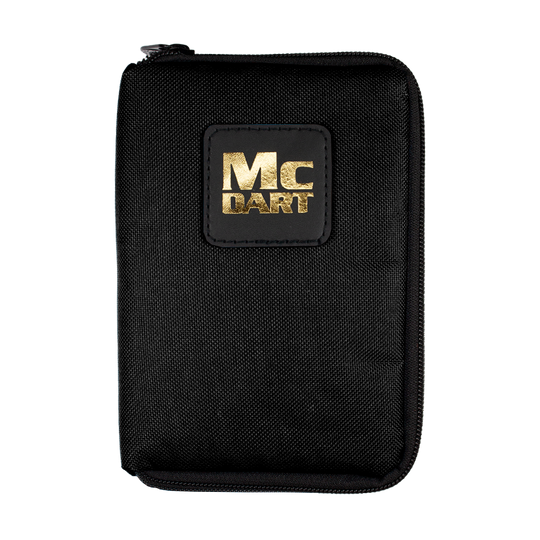 705_McDart_Tasche_Klein_Schwarz_1 Auf dem Bild ist eine schwarze Tasche mit einem Reißverschluss zu sehen. Auf der Vorderseite steht in goldener Schrift "MC DART".