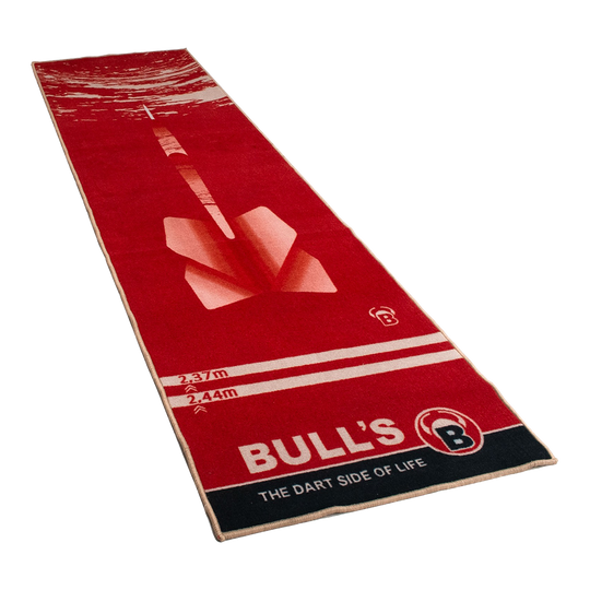 67806_Bulls_Dartteppich_180_Red_1 Dies ist ein roter Teppich mit einem großen Dartpfeil-Motiv in der Mitte. Am unteren Rand steht „BULL'S – THE DART SIDE OF LIFE“.