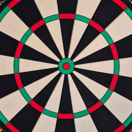 Das Bild zeigt eine Nahaufnahme einer Dartscheibe mit klaren Farbfeldern in Schwarz, Weiß, Rot und Grün. Es handelt sich um das Produkt "Unicorn Eclipse Ultra 2.0 Steeldartboard".
